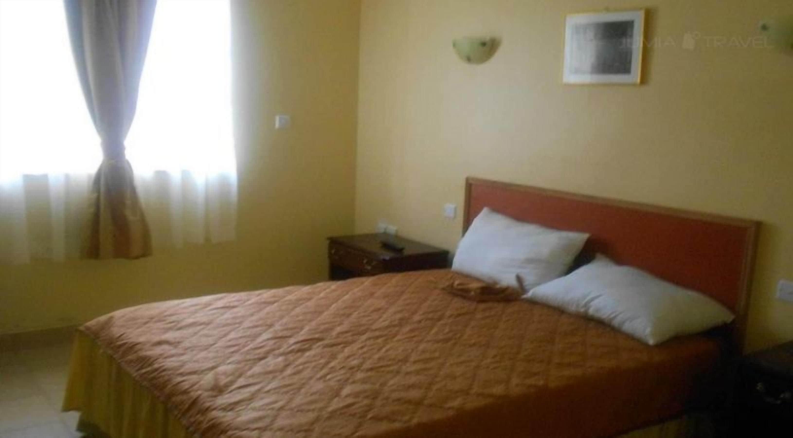 Una cama individual con cabecera de madera en una habitación con paredes amarillas.