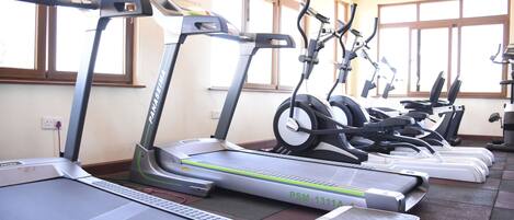 A gym with multiple treadmills and elliptical machines arranged in rows.