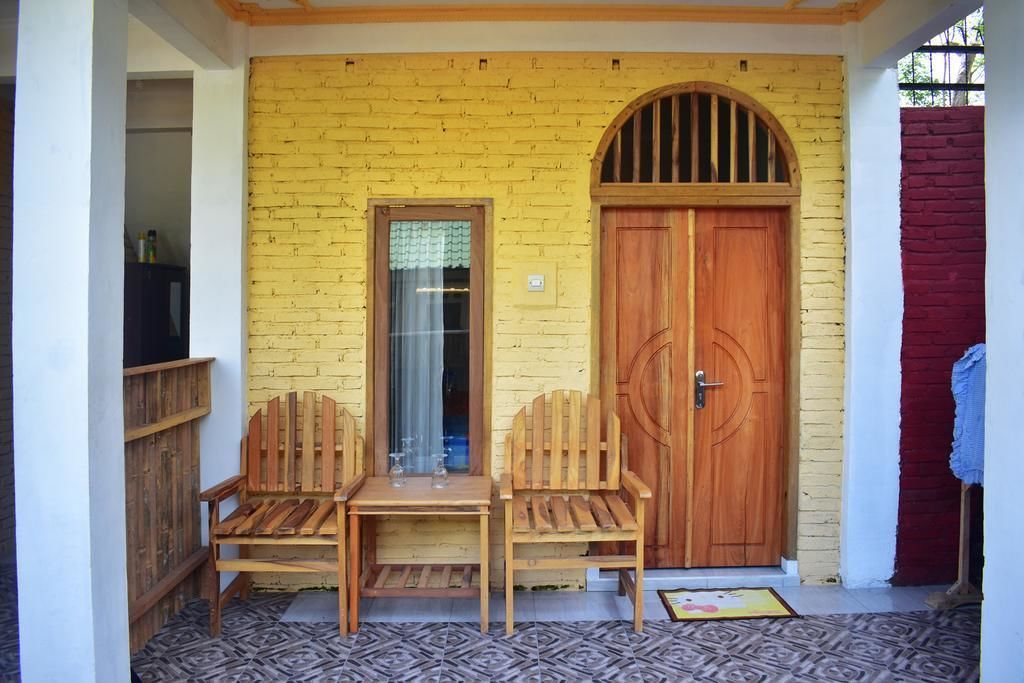 A wooden bench and table set up against a yellow brick wall with a wooden door and window.