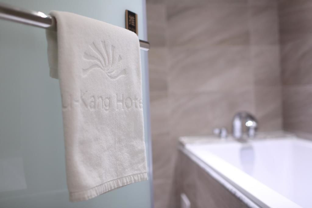 Un baño con una bañera blanca, una toalla colgada en un perchero y una pared con textura.