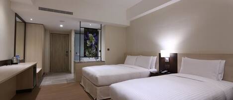 Habitación de hotel con dos camas, un escritorio, un espejo y una ventana con vistas a flores.