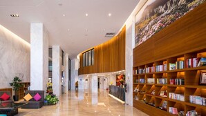Un vestíbulo moderno con paredes de mármol, un mostrador de recepción de madera y una estantería llena de libros.