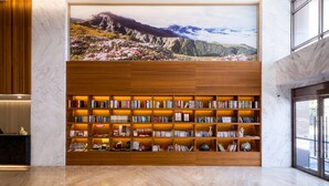 Una biblioteca con estanterías y un cuadro grande con un paisaje de montaña.