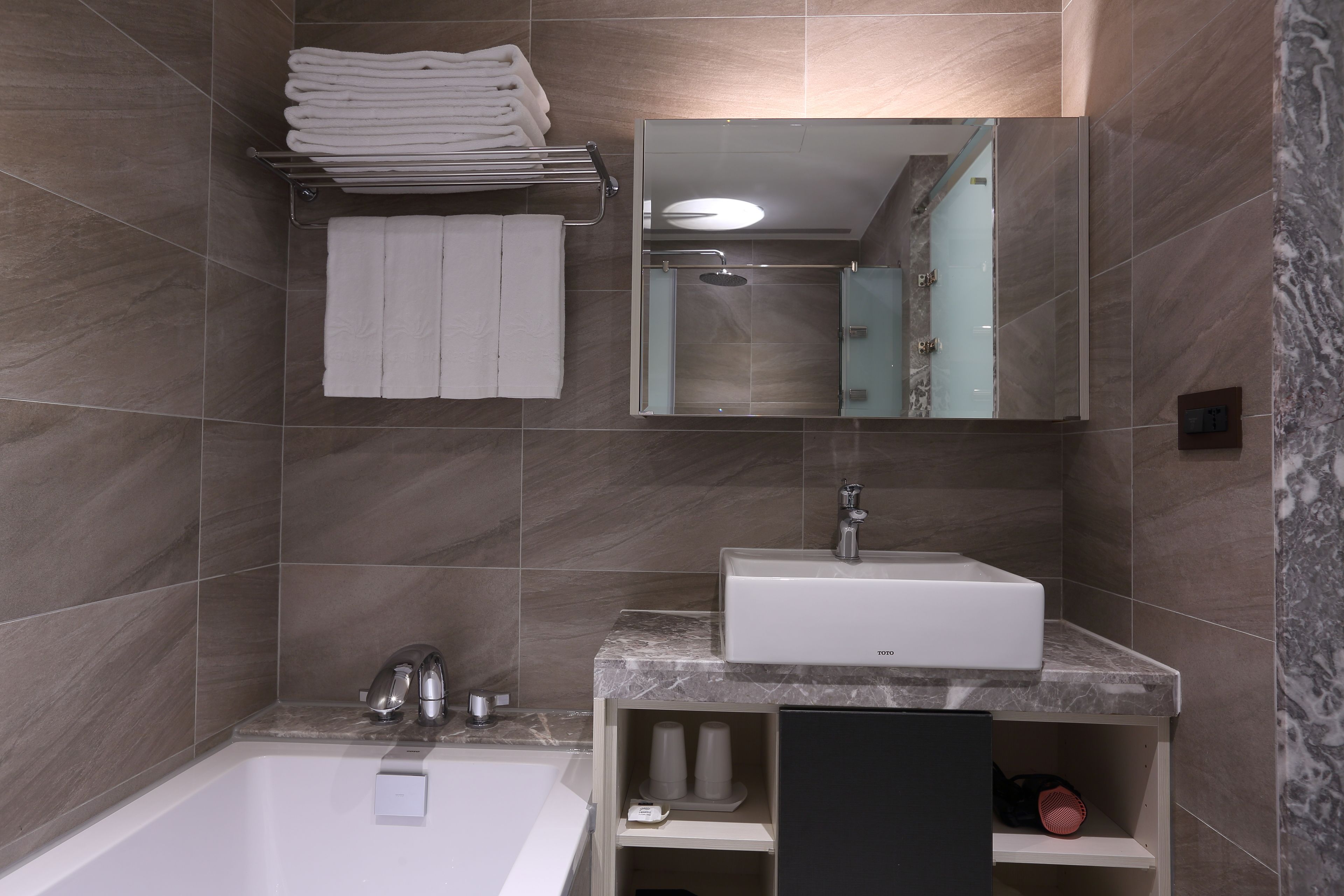 Un baño moderno con bañera, lavamanos, espejo y un perchero para toallas.