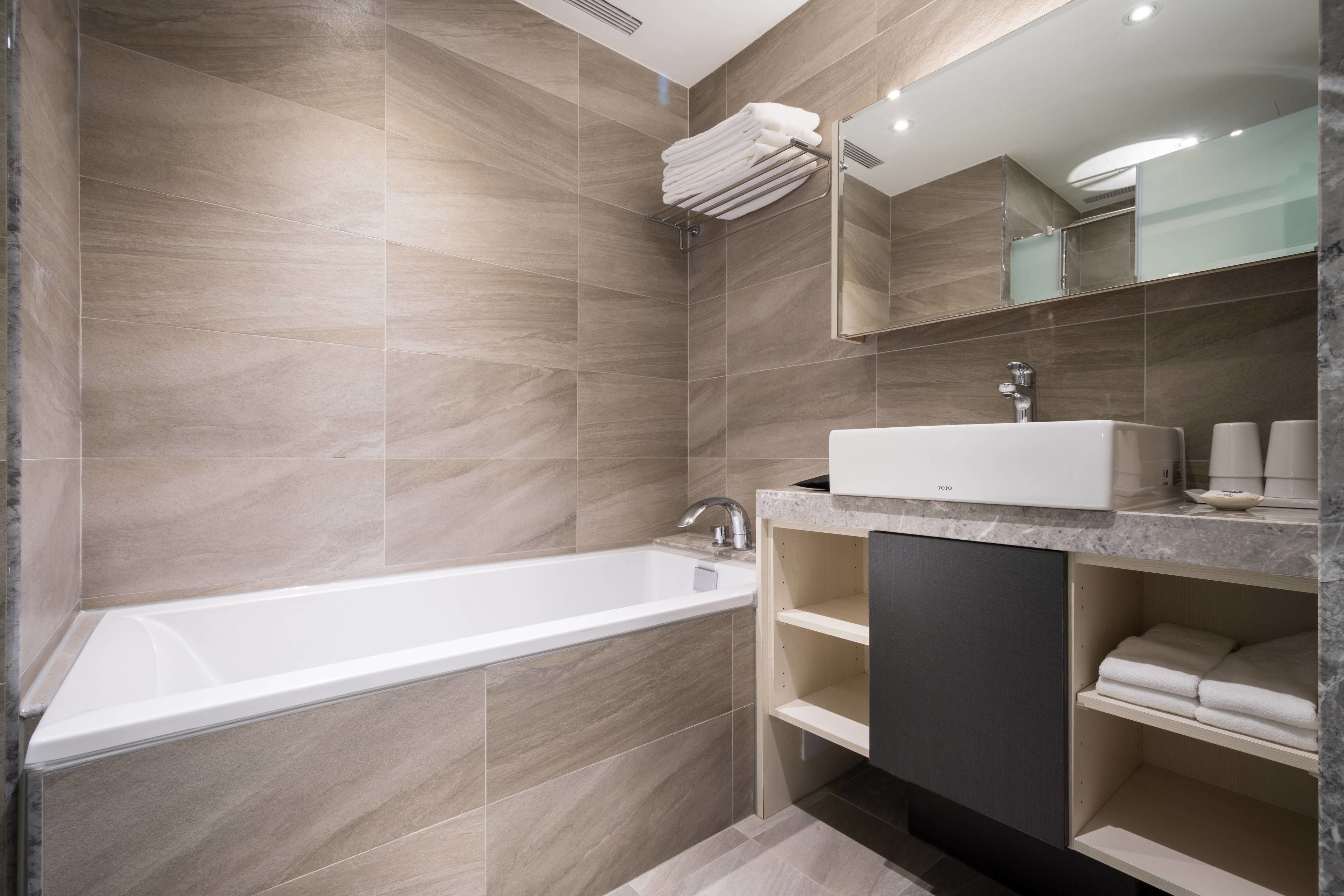A modern bathroom with a large bathtub, a sink with a marble countertop, and a mirror above the sink.