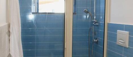 A bathroom with a glass-enclosed shower, a toilet, and a towel hanging on the wall.