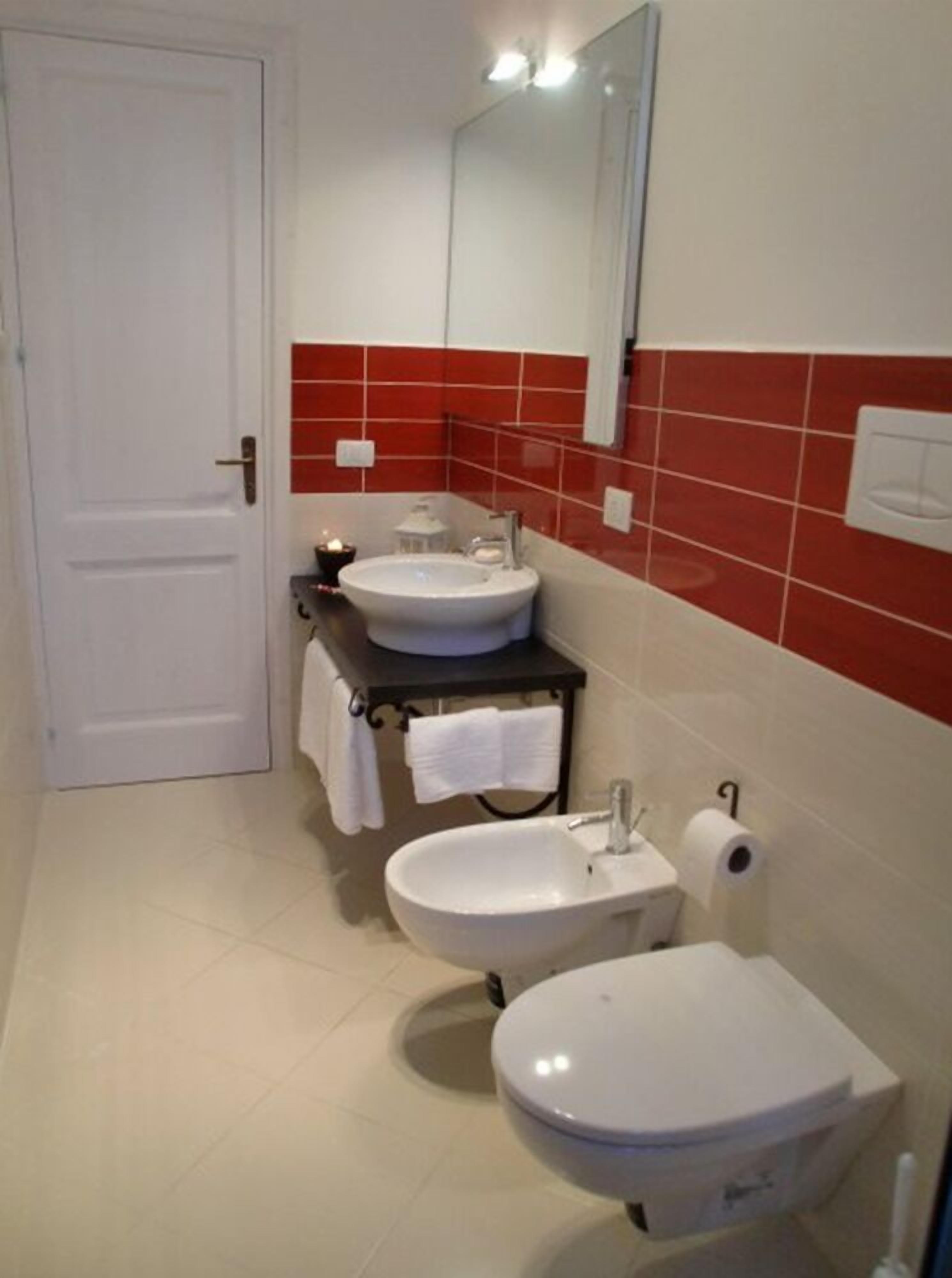 A bathroom with a white door, two sinks, a toilet, and a mirror.
