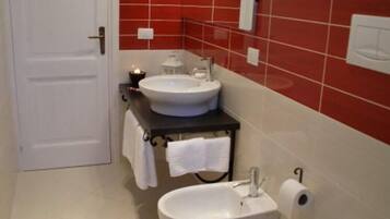 A bathroom with a white door, two sinks, a toilet, and a mirror.