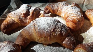 Diversos pastéis, incluindo croissants e outros produtos de panificação, polvilhados com açúcar em pó.