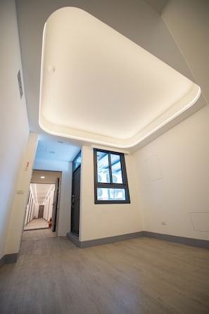 A modern interior with a high ceiling, a large window, and a hallway leading to another room. - Shan Shui Hotel (Hualien City)