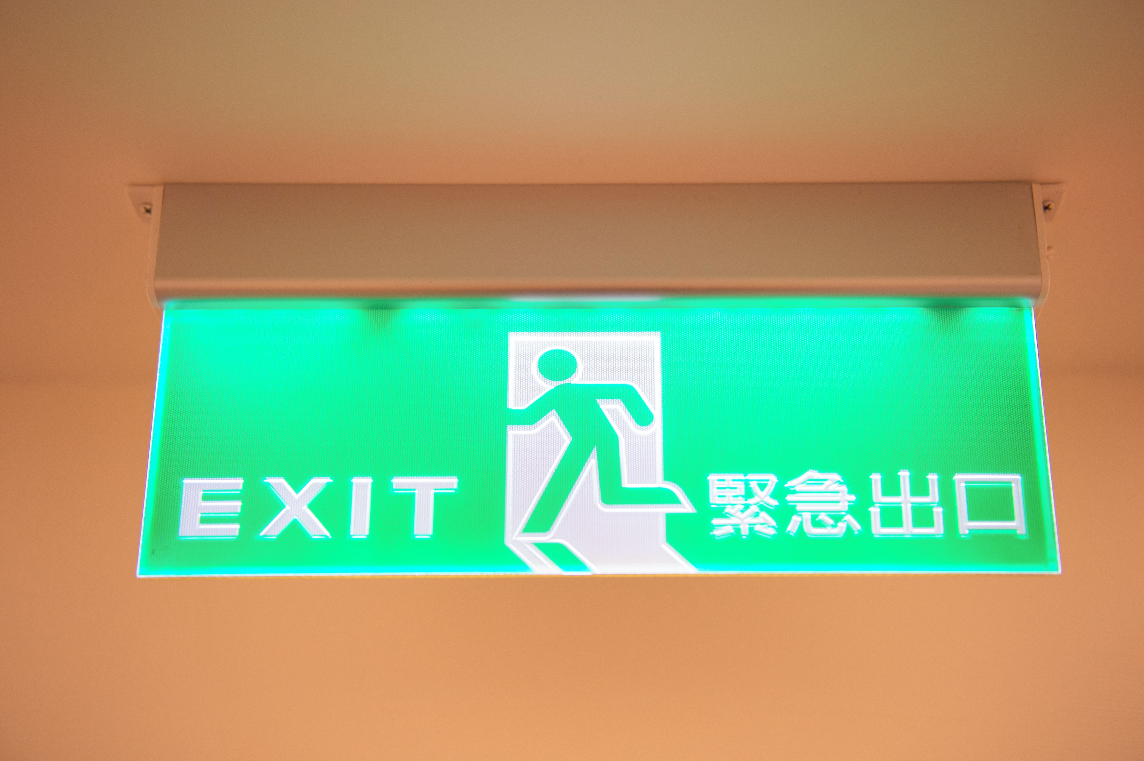 An exit sign with a figure running towards an exit, and the words 'EXIT' and 'Emergency Exit' in English and Chinese.