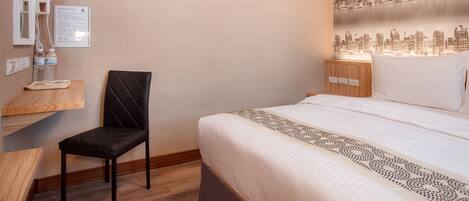 A hotel room with a bed, a chair, a nightstand, a wall-mounted mirror, and a cityscape wallpaper.