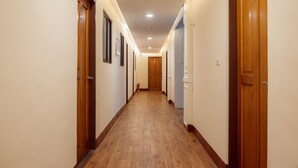 Pasillo de hotel con suelo de madera, puertas a ambos lados e iluminación empotrada.