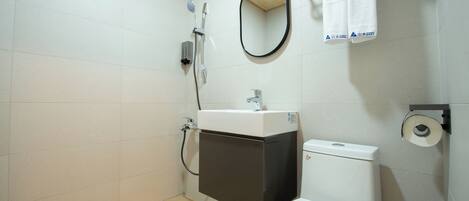 Un baño con inodoro, lavamanos, espejo y ducha.