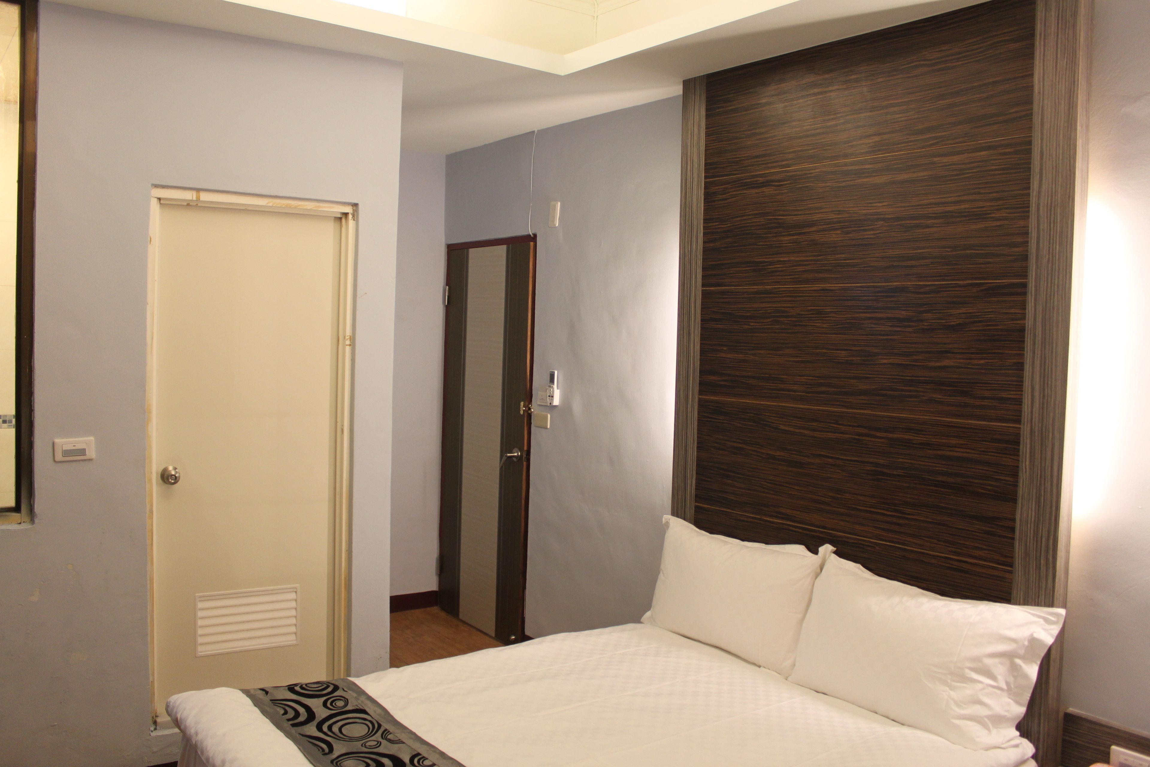 Une chambre d’hôtel avec un lit, une porte et une tête de lit en bois.