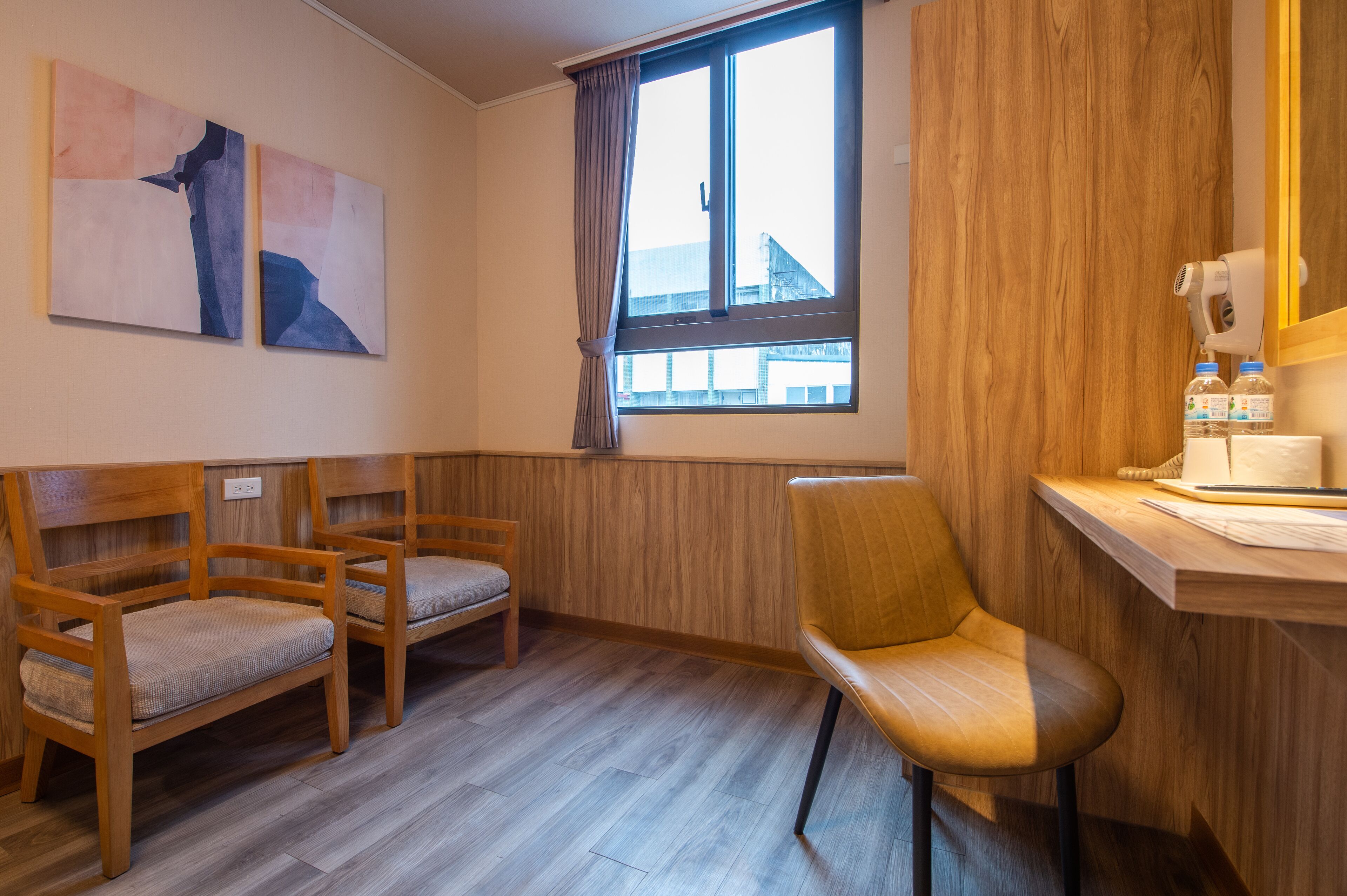 Una habitación con muebles de madera, una ventana con cortinas y cuadros en la pared.