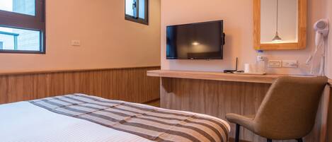 Habitación de hotel con una cama, un escritorio con televisor, una silla y un espejo.