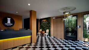 A hotel reception area with a checkered floor, a reception desk with a logo, and a seating area with chairs and a small table. - The O-Zone Airport Inn (Bangkok)