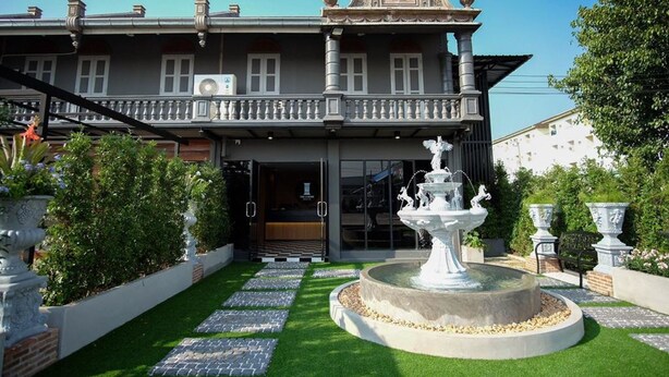 A two-story building with a balcony, a fountain, and a well-maintained garden. - The O-Zone Airport Inn (Bangkok)