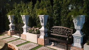 A garden pathway with a bench, surrounded by brick planters and greenery. - The O-Zone Airport Inn (Bangkok)