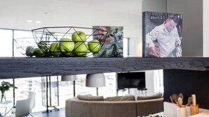 Una cocina moderna con una frutera de alambre en la encimera, un libro de cocina y un televisor.
