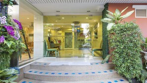 A hotel entrance with a glass door, a staircase with blue accents, and potted plants. - Orchid Resort (Bangkok)