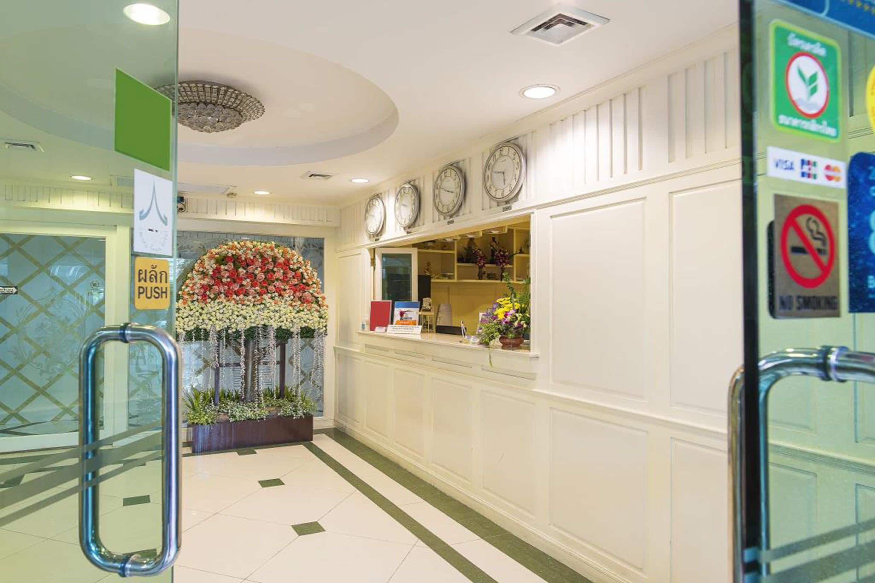 A reception area with a floral display, clocks, and a 'No Smoking' sign.
