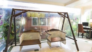 A room with a large window, a desk, and two wicker swing chairs. - Orchid Resort (Bangkok)