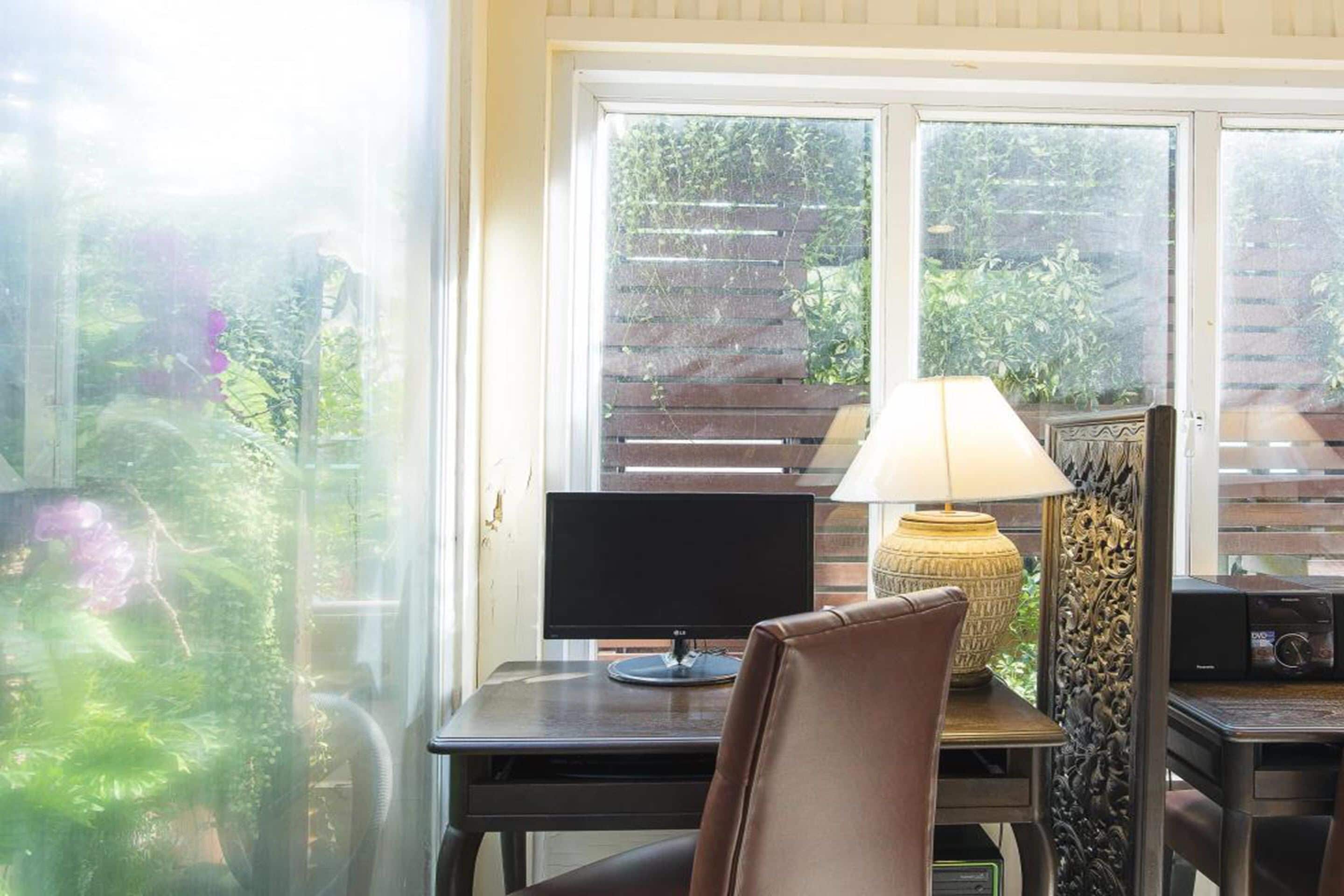 A room with a desk, a computer, a lamp, and a chair.