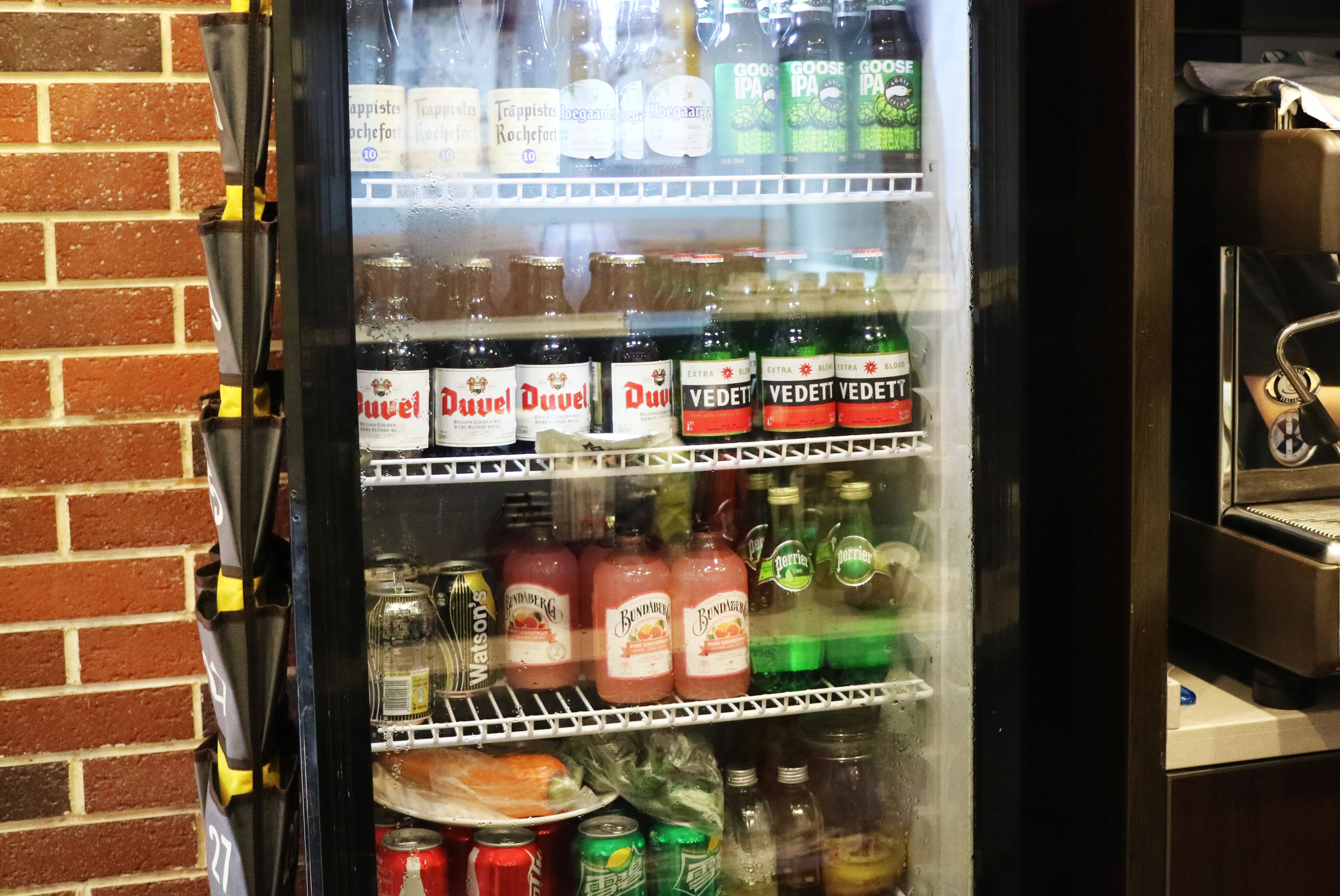 Een drankkoelkast gevuld met diverse dranken, waaronder Duvel, Vedett en Goose IPA.