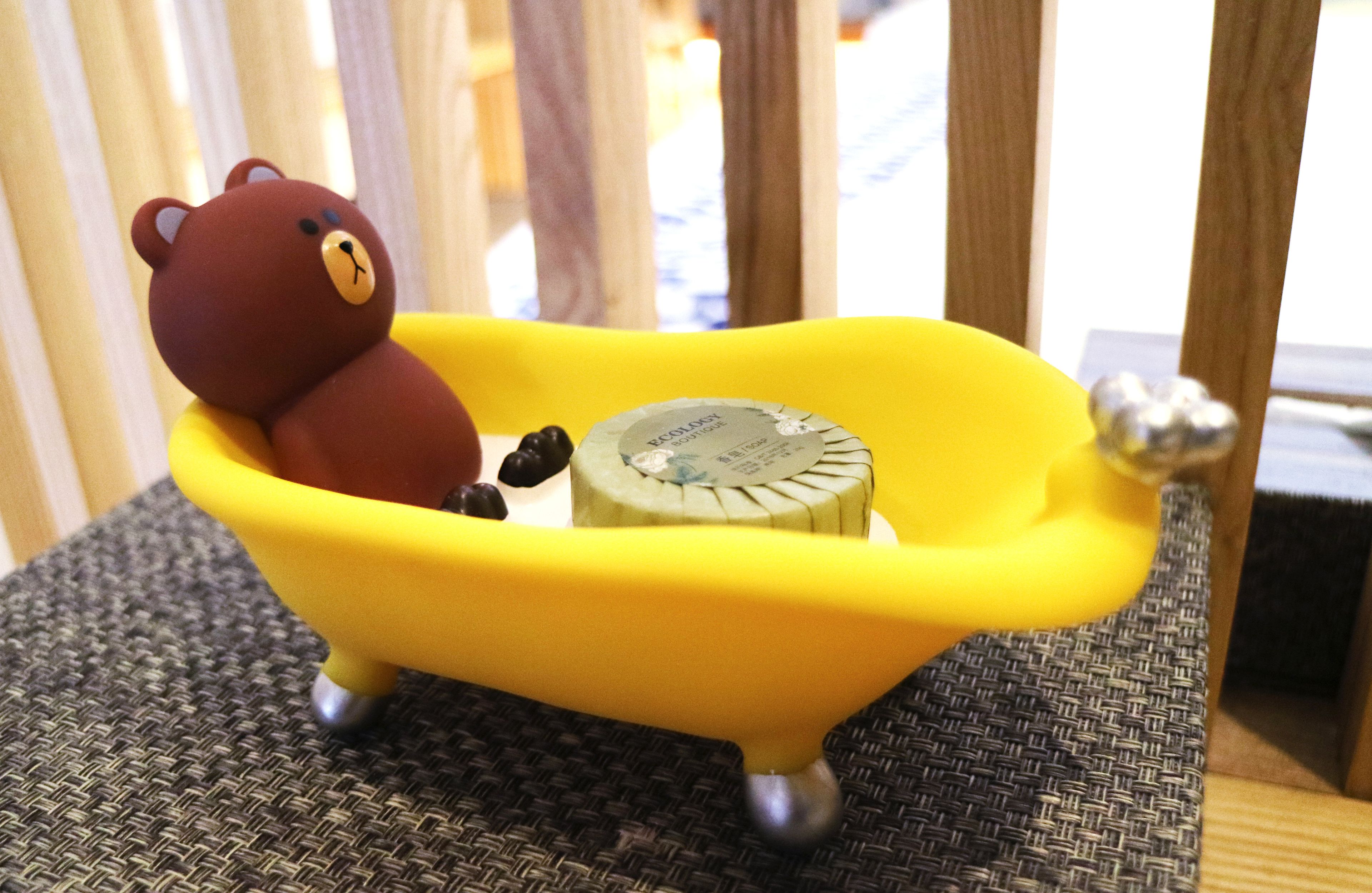 A small yellow bathtub with a teddy bear and a soap bar.