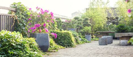 A paved pathway lined with large planters and lush greenery.