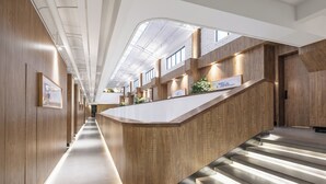 A modern interior with a central wooden reception desk, a staircase, and a skylight. - Lin Yin Art Hotel Shanghai PVG Airport Disneyland Free Shuttle (Shanghai)