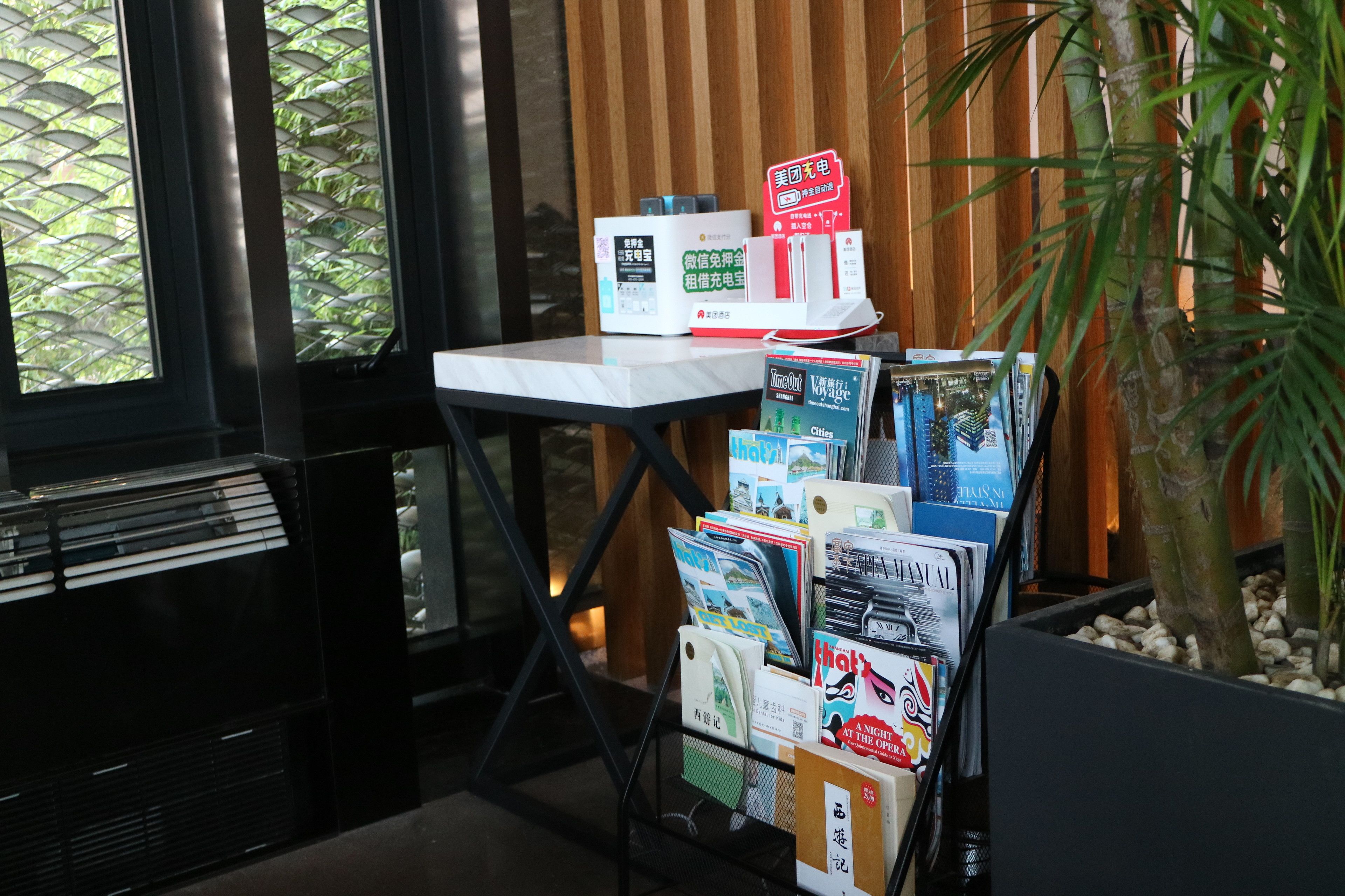 A reception desk with a computer, a plant, and a display of magazines.