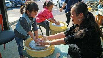 A pottery wheel with two children and an adult.