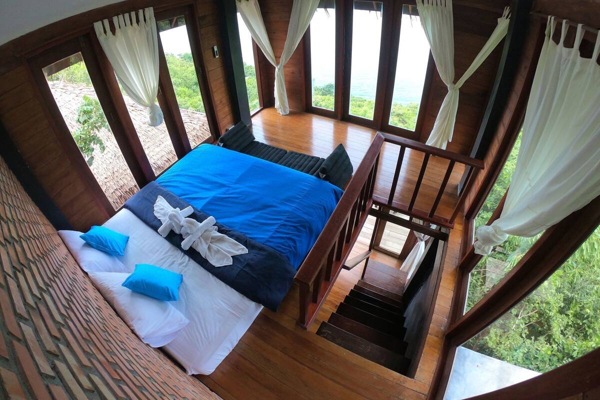 A bedroom with a bed, pillows, and curtains.