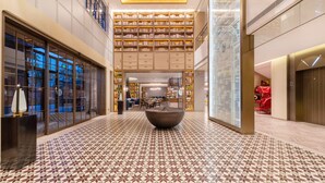 A spacious lobby with a patterned floor, a central seating area, and a large bookshelf filled with books. - Melia Shanghai Parkside (Shanghai)