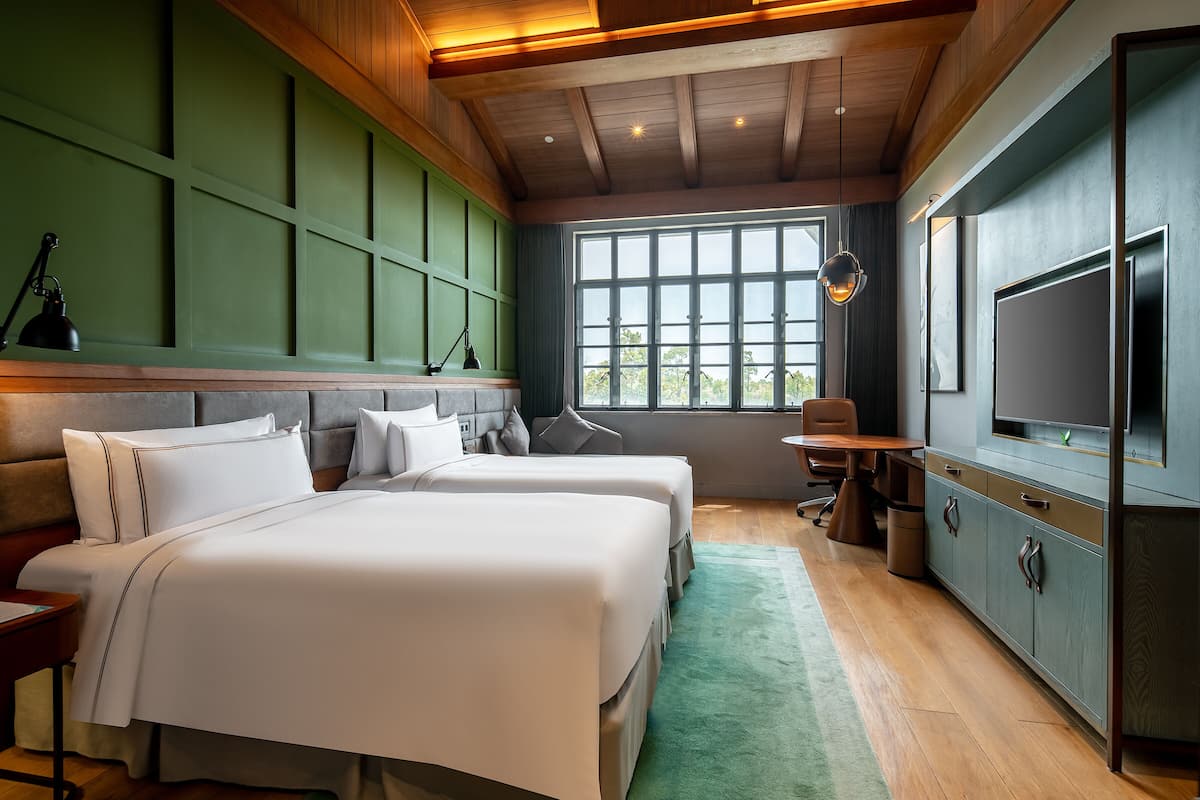 A modern hotel room with a large bed, a desk, a television, and a view of the outdoors.