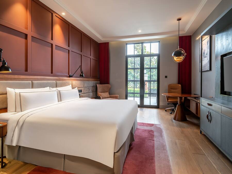 Quarto de hotel moderno com uma cama grande, uma escrivaninha e uma televisão.