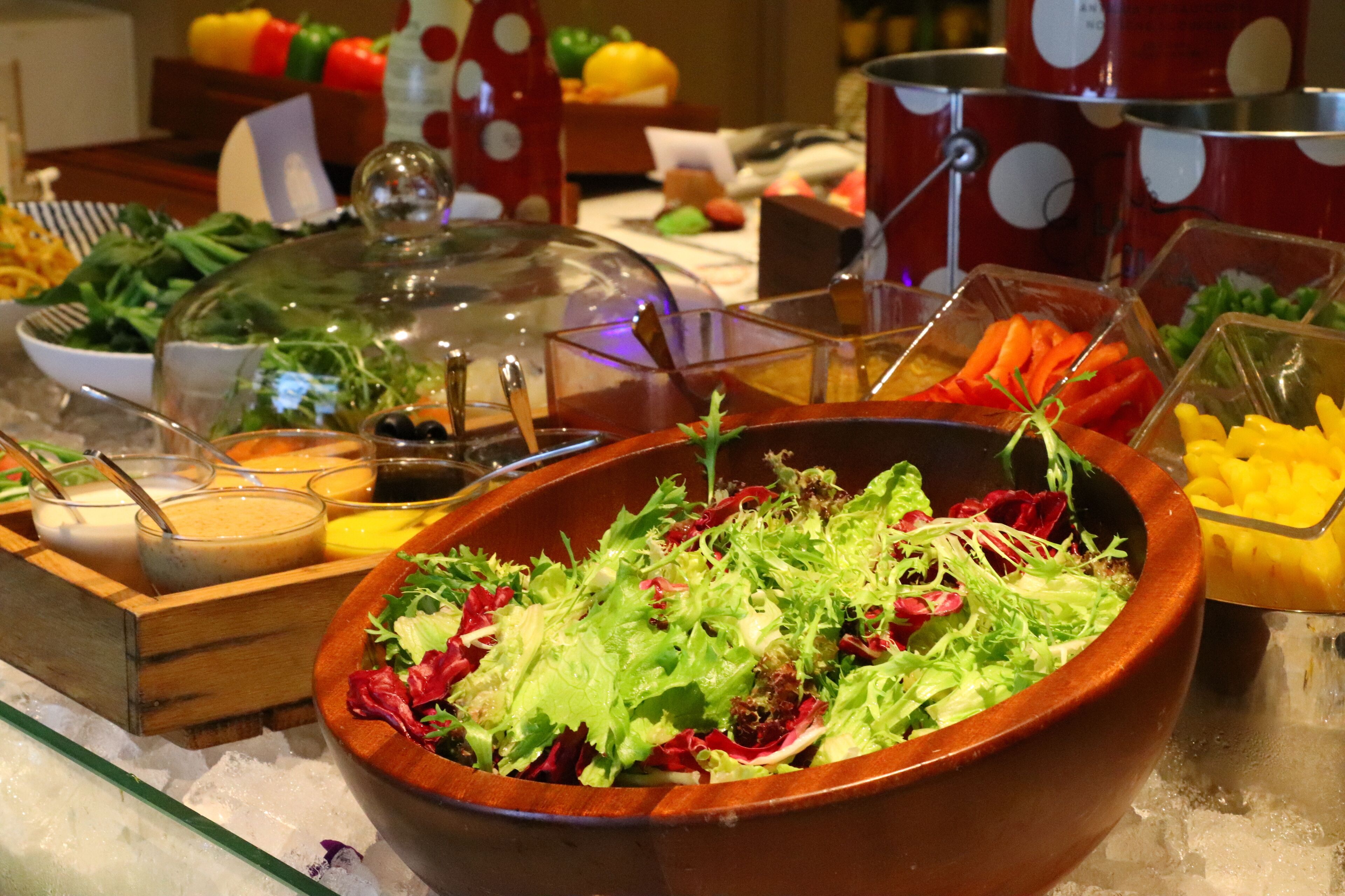 A buffet with various food items and a salad bowl in the center.