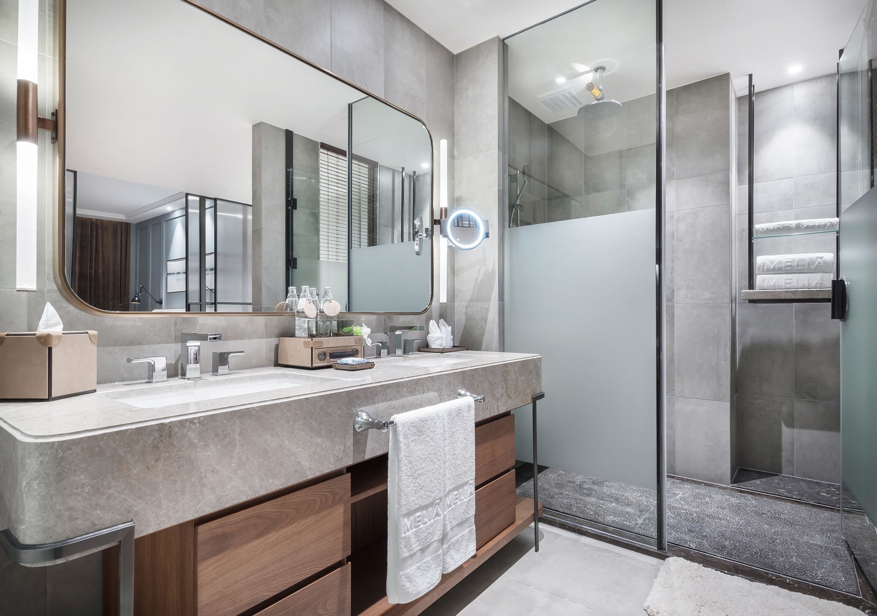Une salle de bain moderne avec un grand miroir, un meuble-lavabo avec une serviette et une cabine de douche en verre.