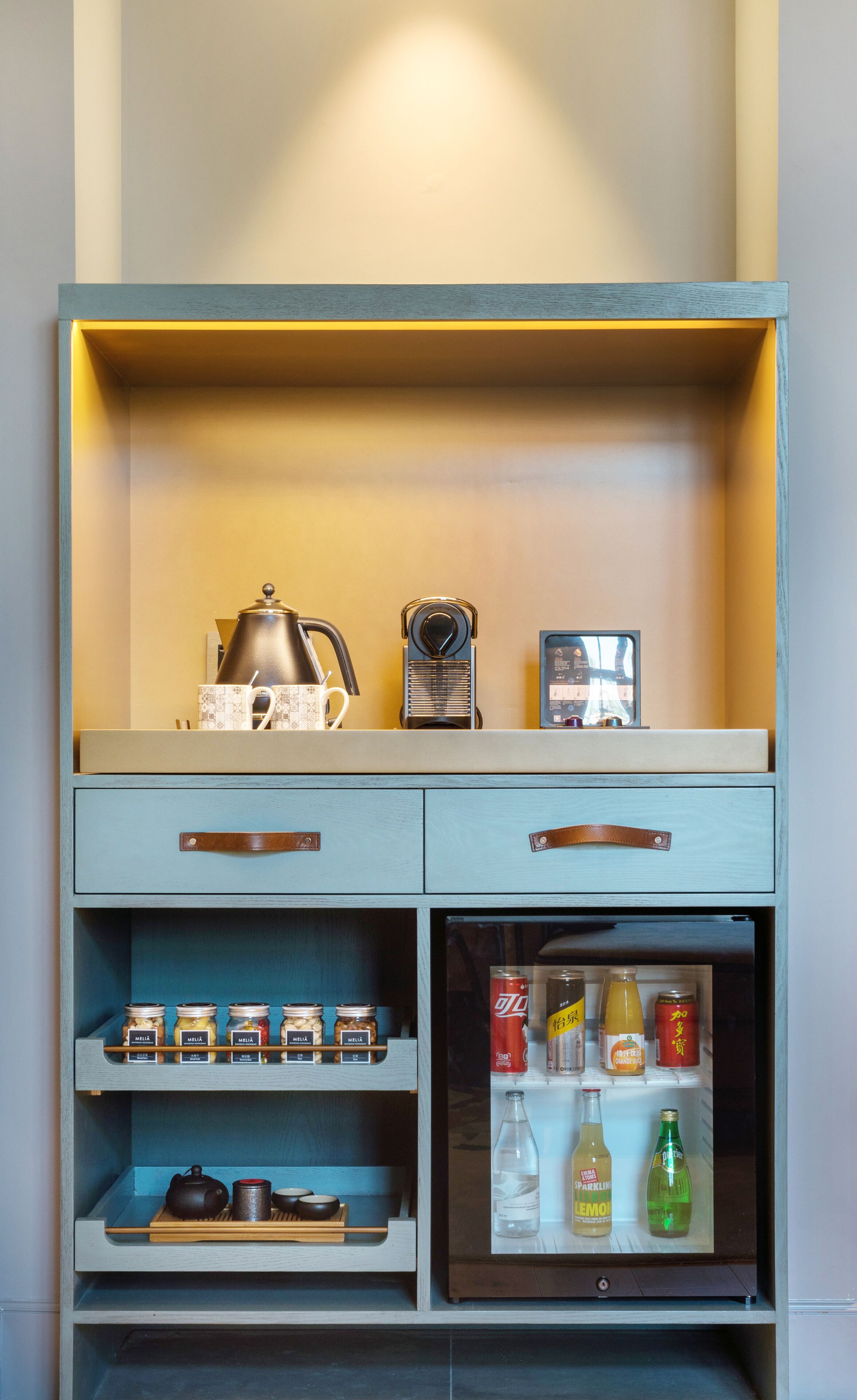 A kitchenette with a coffee maker, tea kettle, and a small refrigerator containing beverages.