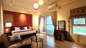 Quarto de hotel com uma cama, um sofá, uma mesa pequena, um espelho e vista para o exterior.