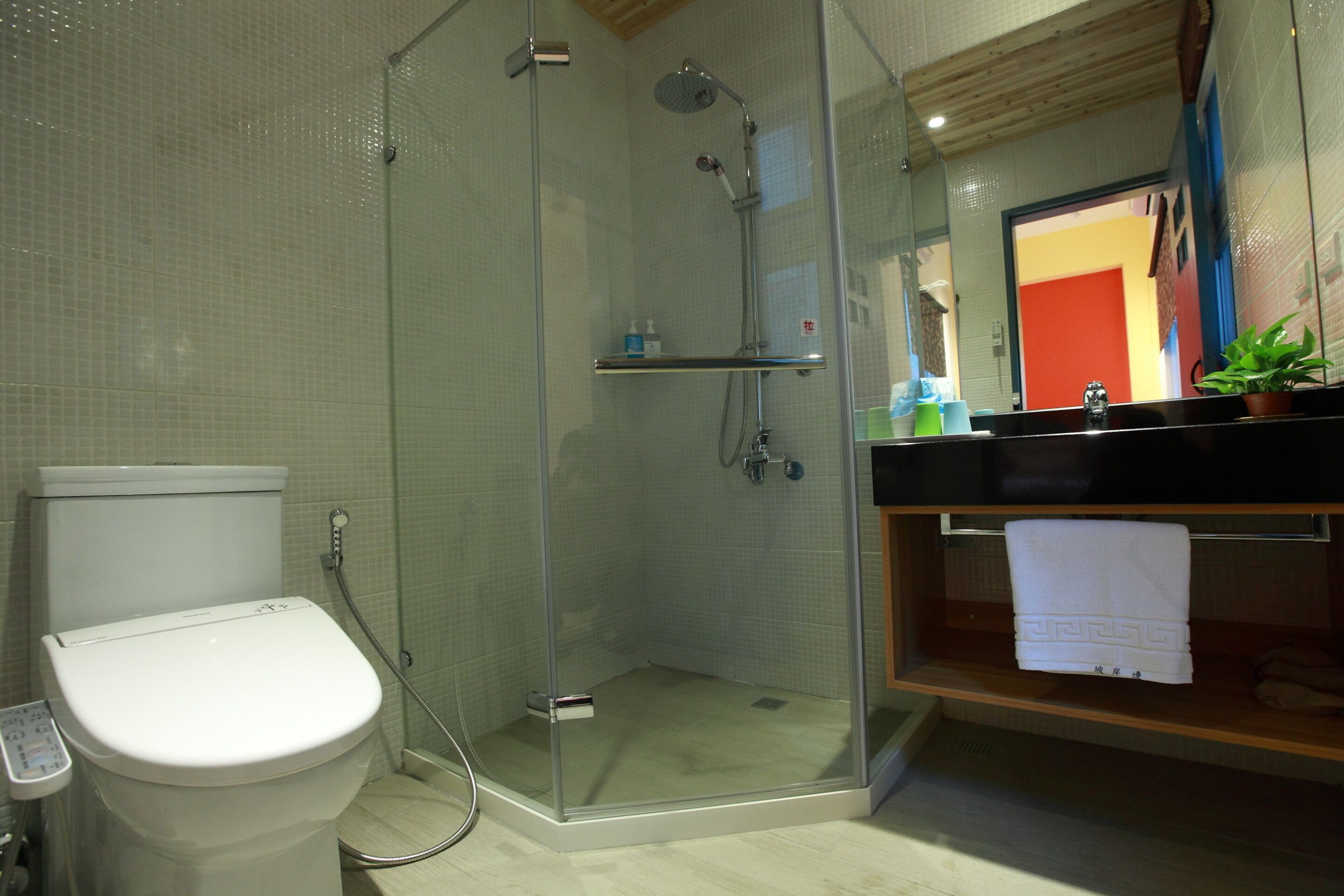 A modern bathroom with a glass-enclosed shower, a toilet, and a sink with a towel rack.