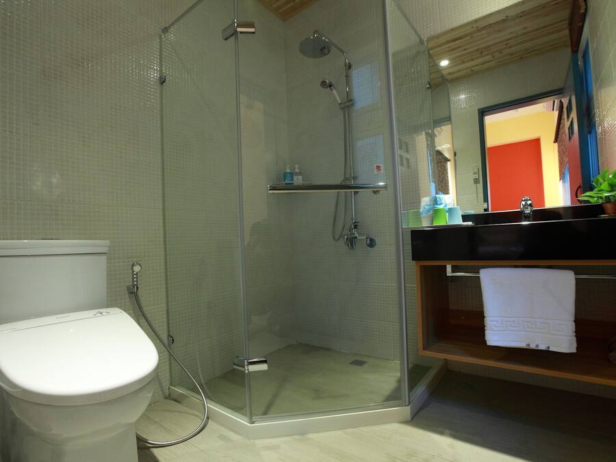 A modern bathroom with a glass-enclosed shower, a toilet, and a sink with a towel rack.