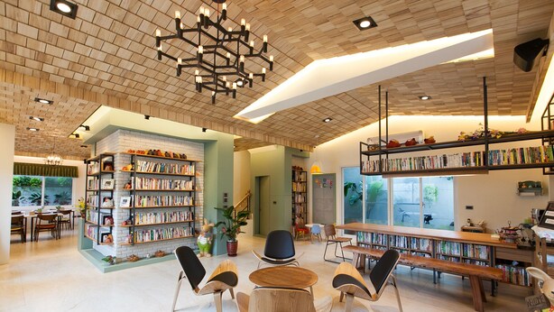 Uma biblioteca ampla com várias estantes, assentos confortáveis e um design de teto moderno.