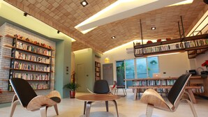 Uma biblioteca moderna com estantes, assentos confortáveis e teto iluminado.