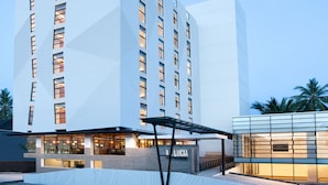 Um hotel moderno com fachada geométrica, vários andares e área de entrada coberta.