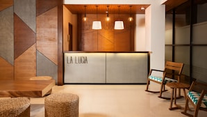 Uma área de recepção com um balcão de madeira, três luminárias pendentes e duas cadeiras de vime.