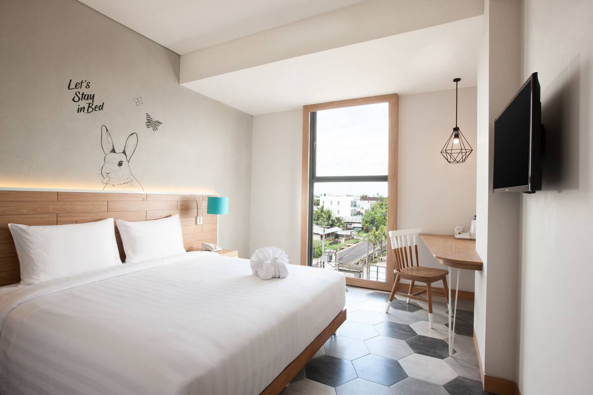 A modern hotel room with a large bed, a desk, and a TV.